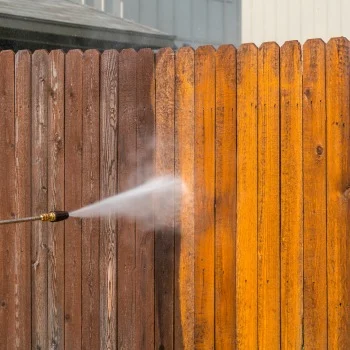 Pressure washing a wooden fence, revealing a clean, bright section next to a weathered area; concept of pressure washing Wilmington NC.