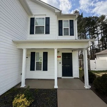Clean white two-story house with dark shutters and a tidy entrance. Perfect example of pressure washing Wilmington NC services.