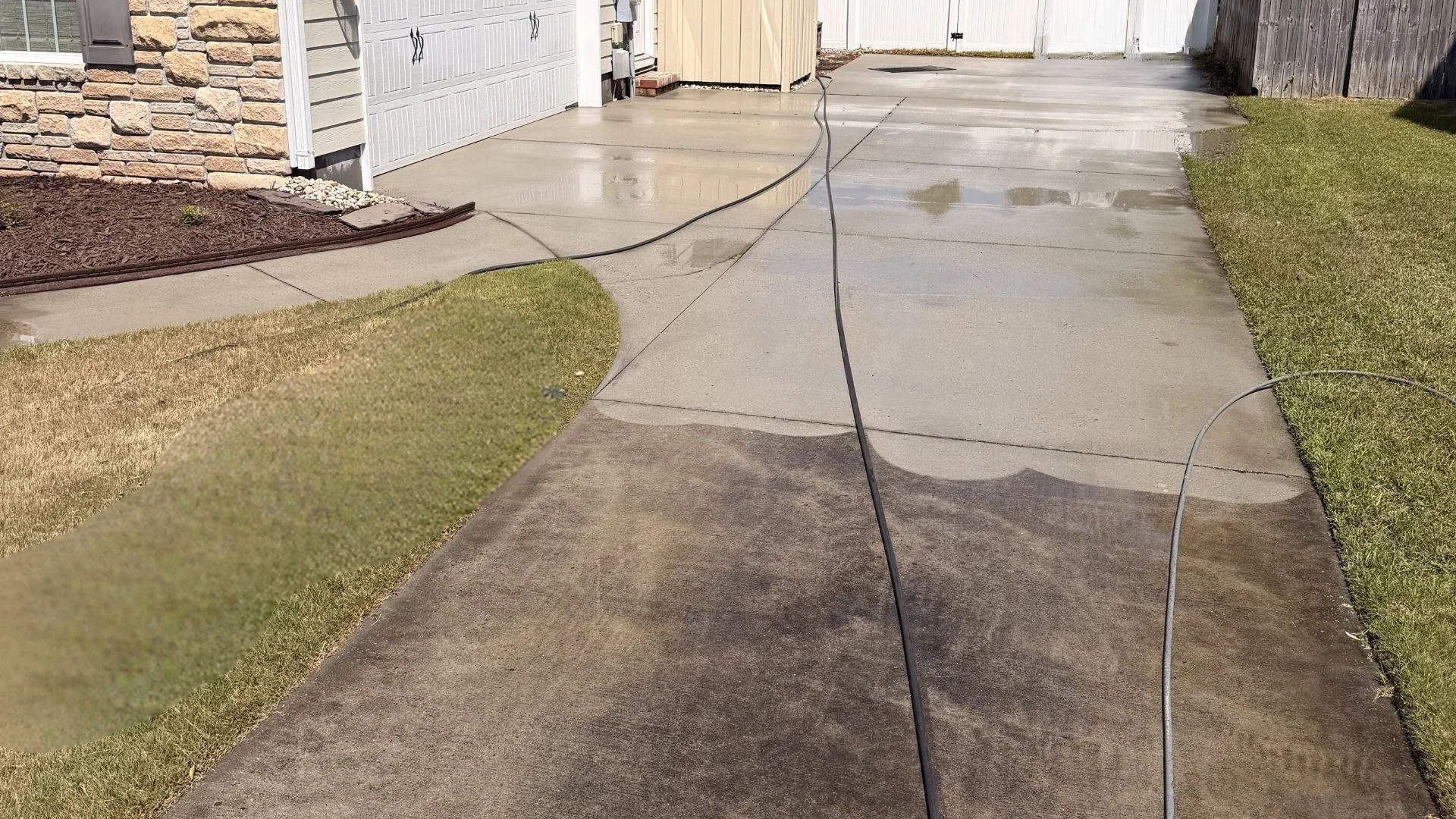 Driveway partially cleaned using pressure washing Wilmington NC; visible contrast between clean and dirty concrete surfaces.